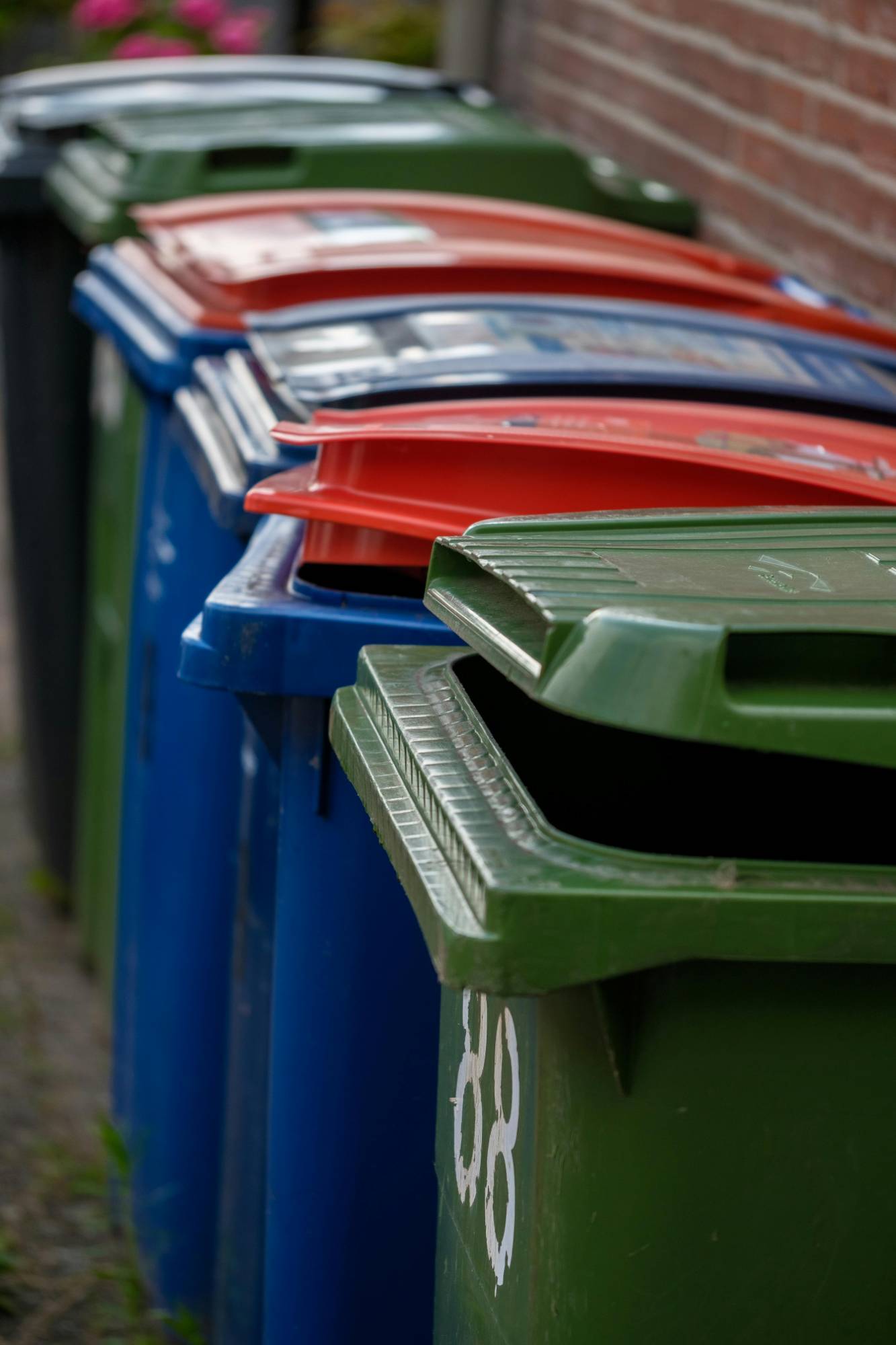 A row of municipal recycling and trash bins