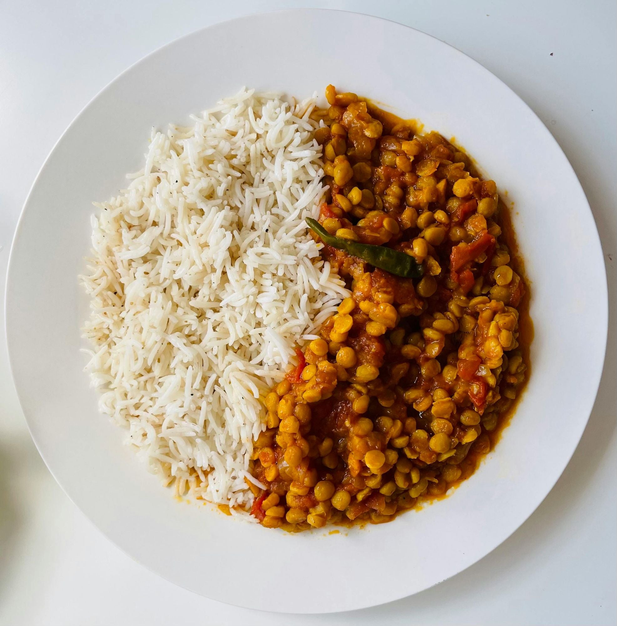 a white bowl with a lentil curry and white rice