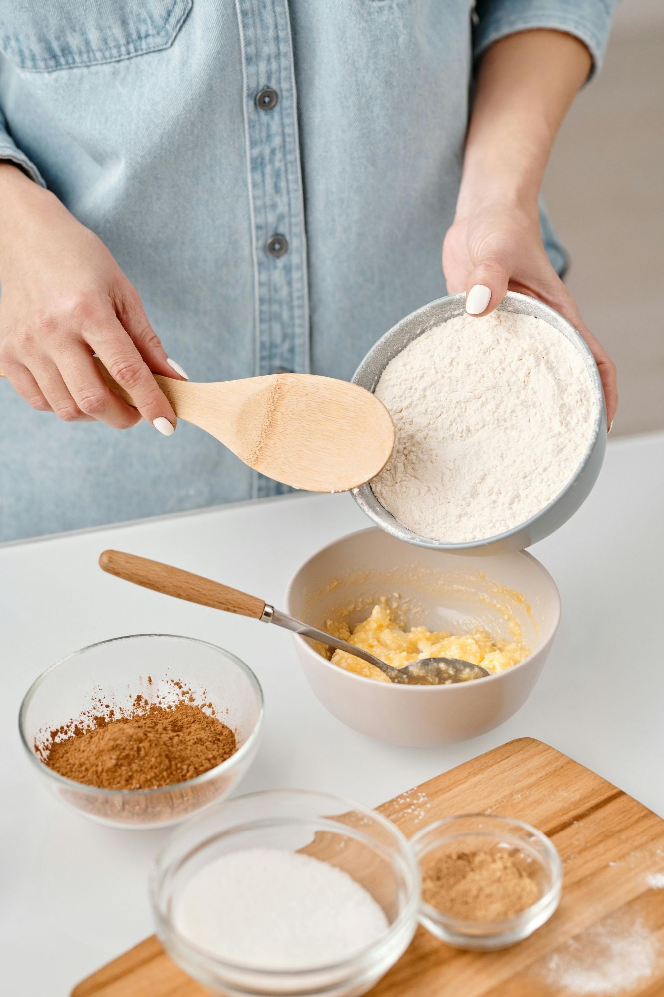 A baker mixing dry ingredients into wet ingredients