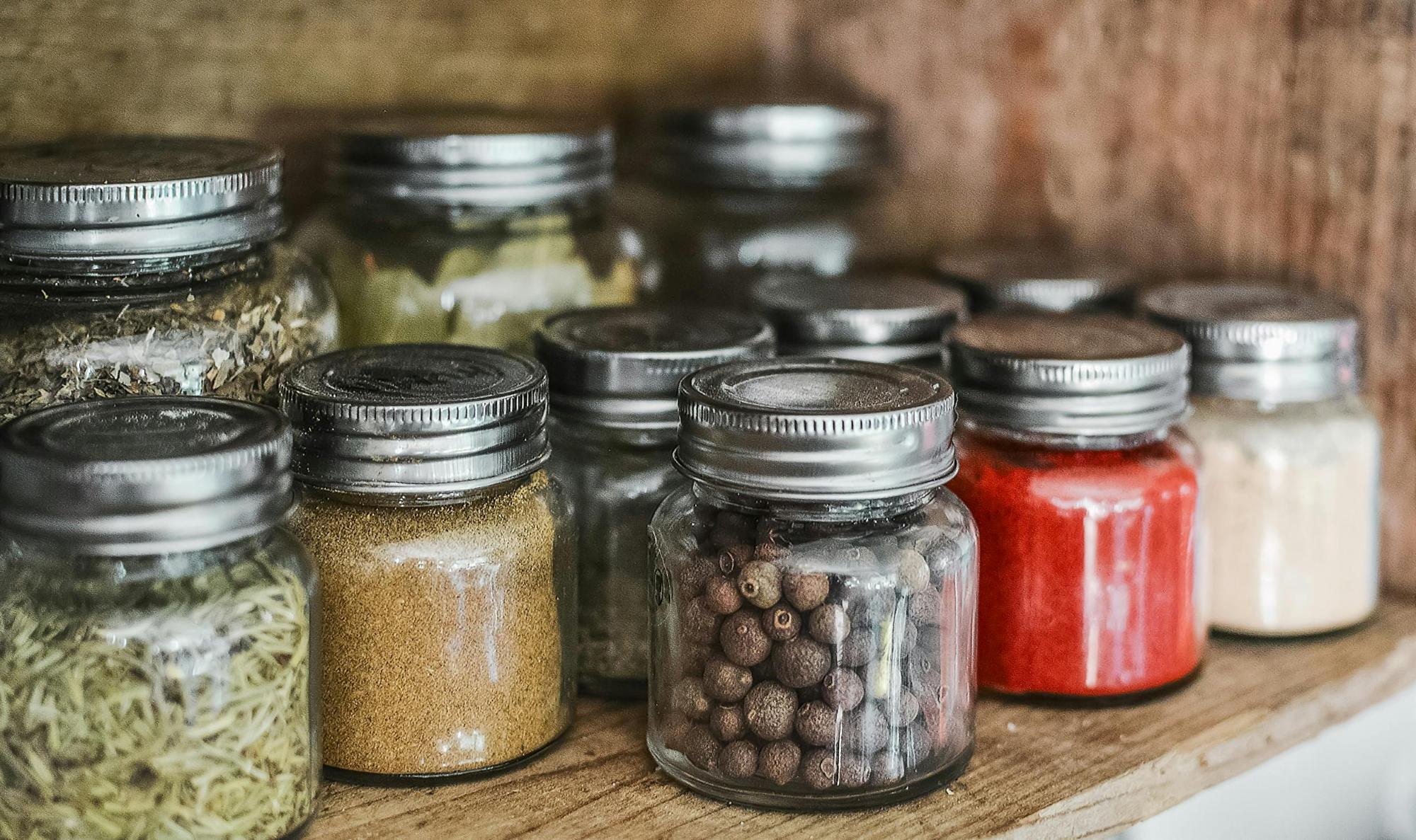 Glass jars of dried spices in a pantry cabinet