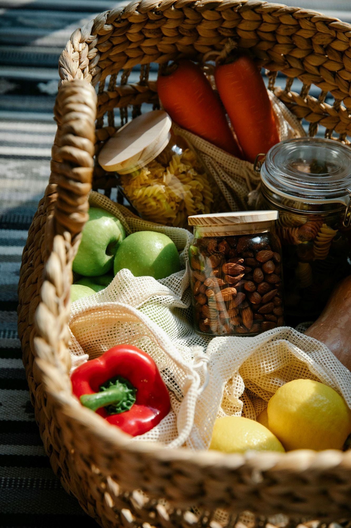 A woven basket full of bags of produce and jars of dry goods