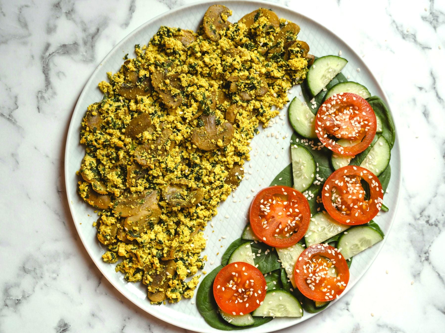 A tofu scramble with mushrooms on a place with a salad