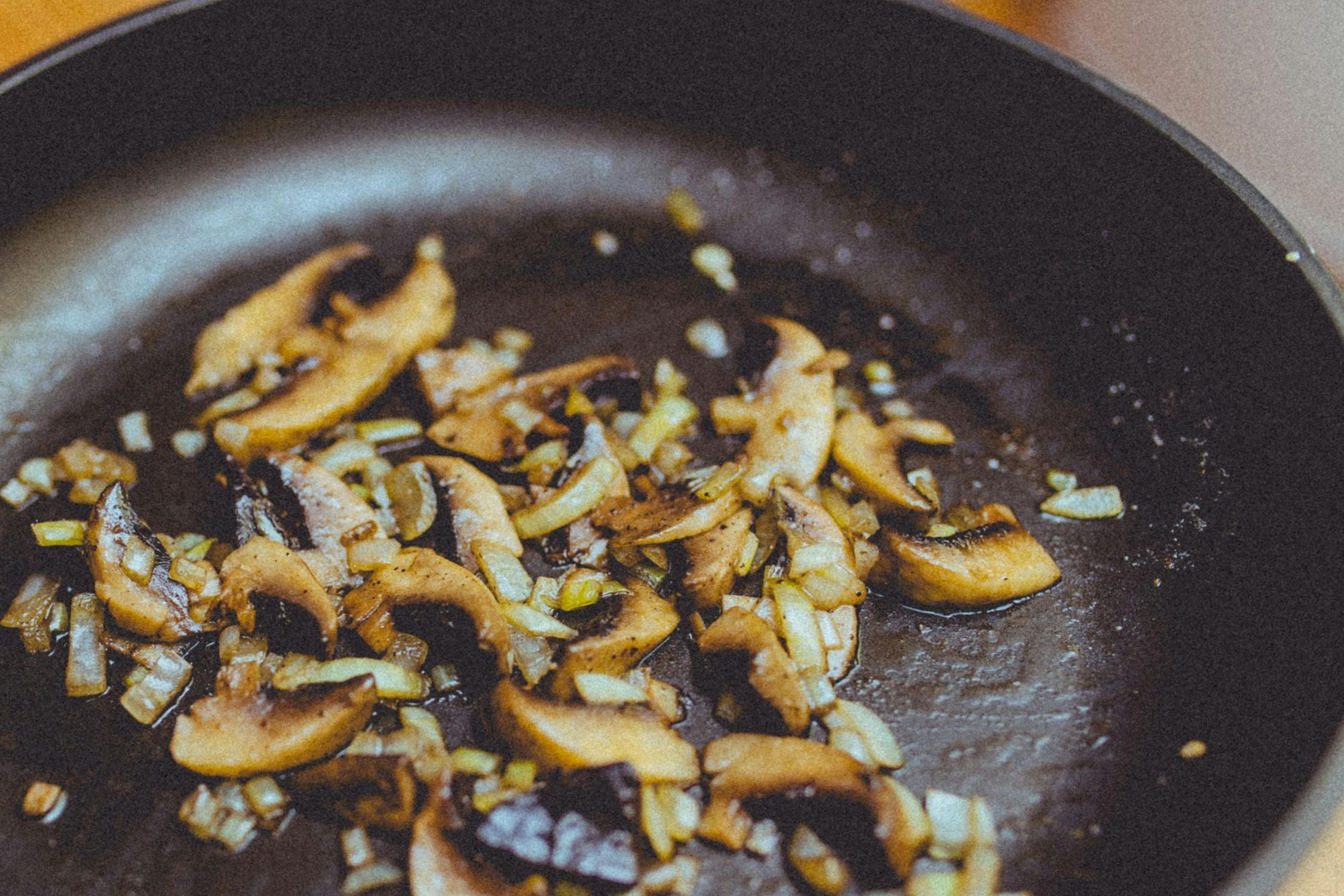 onions and mushrooms frying in a pan with avocado oil