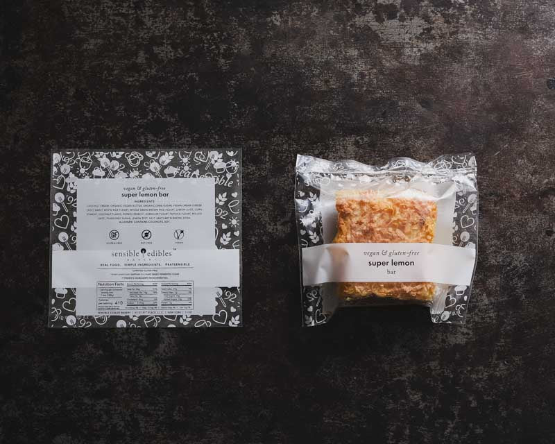 Packaged lemon bar, labeled 'super lemon bar', next to its packaging showing nutrition facts and ingredients.