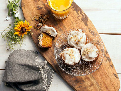 Vegan & Gluten-Free Carrot Walnut Muffin with Cream Cheese Frosting on a Glass Plate and Cup of Orange Juice