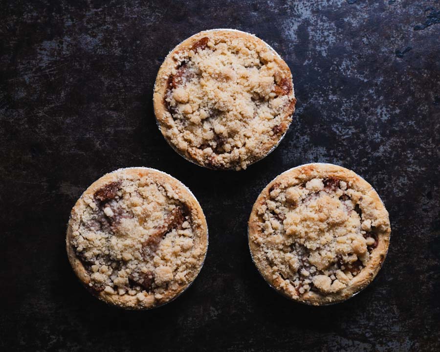 3 mini apple crumb pies on a black background