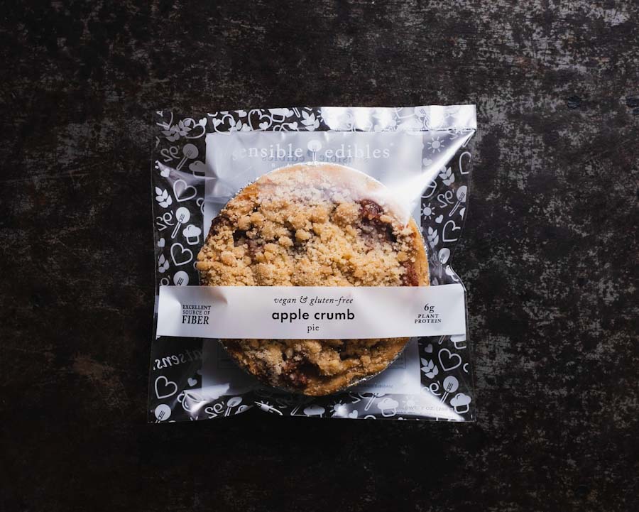 Packaged mini apple crumb pie on a black background