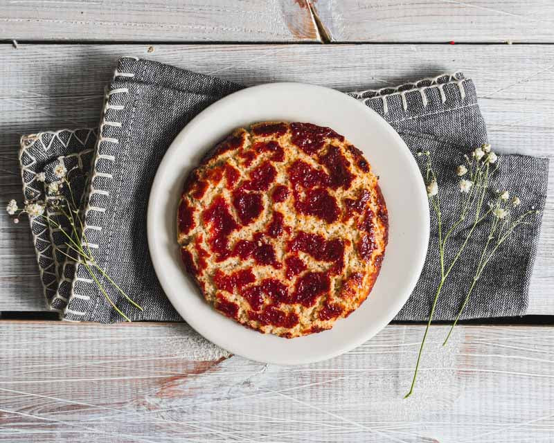 Raspberry crinkle cookie on a white plate with decorative fabric and flowers.